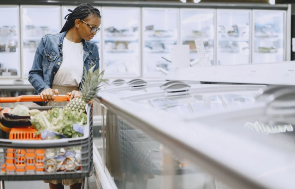 Imagem de cliente em super mercado olhando para produtos da Noronha Alimentos em um freezer